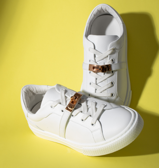 white hermes sneakers on a yellow background